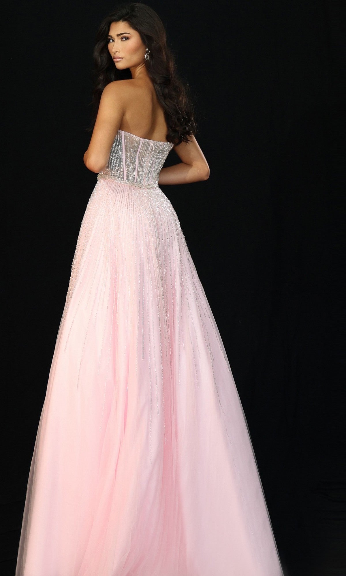A woman stands against a black background wearing the Jovani 45885 long prom dress—a pink, strapless, floor-length A-line gown with a beaded fitted bodice and flowing tulle skirt.